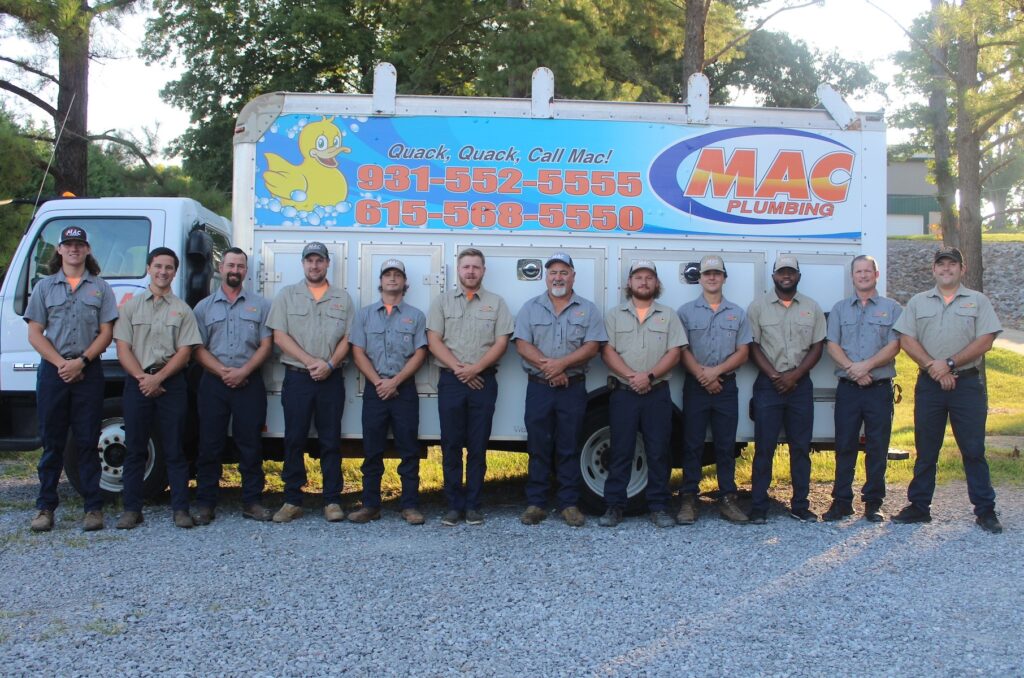 Mac Plumbing Heating & Air team in Clarksville, TN standing in front of a Mac truck